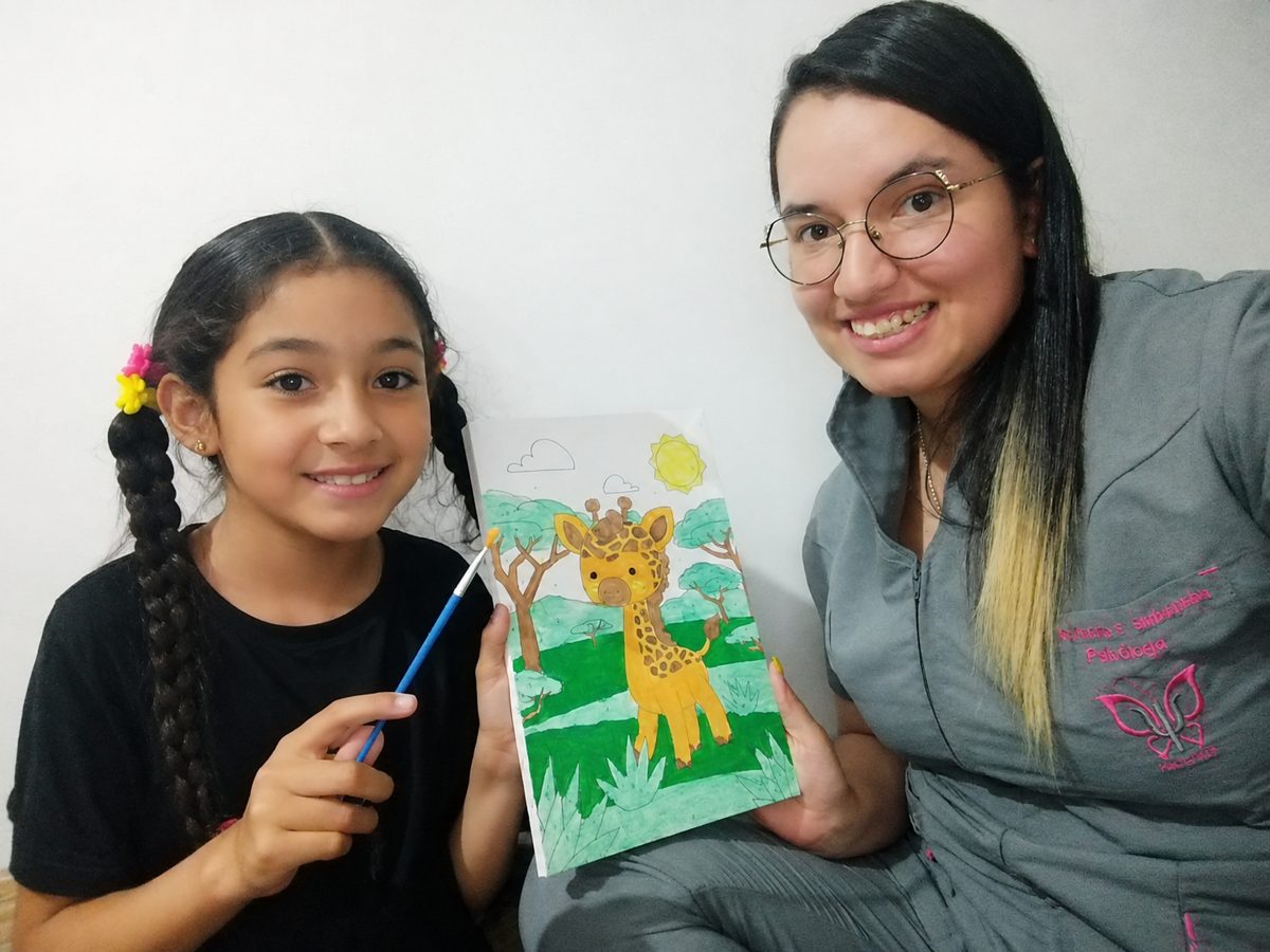 Niña en terapia infantil mostrando su dibujo — Psiconfiar